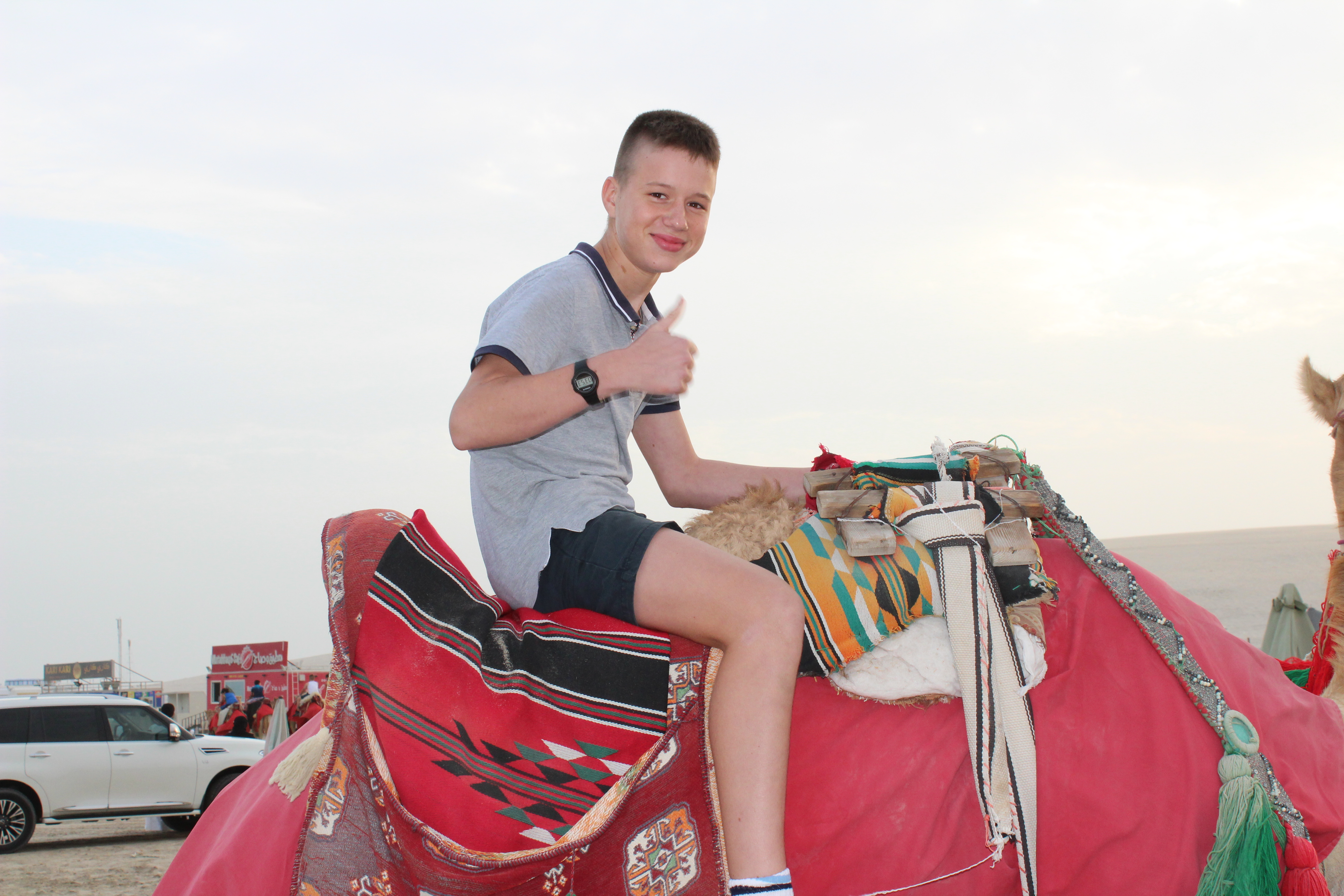 student giving thumbs up while riding camel